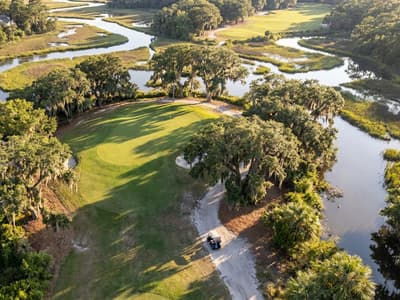 Aerial view of the South Carolina coastline along the Grand Strand, with beachfront high-rises giving way to marsh, tidal creeks, and pine-lined golf holes inland.