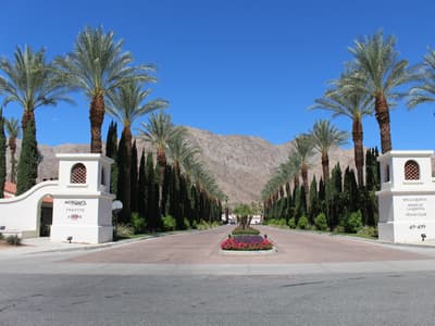 Desert golf hole at PGA West in La Quinta, California, with bunkering, palm trees, and the Santa Rosa Mountains rising behind the green.