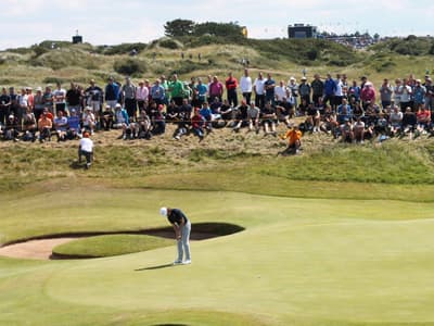 Spectators watching a golfer putt on a green during a golf tournament